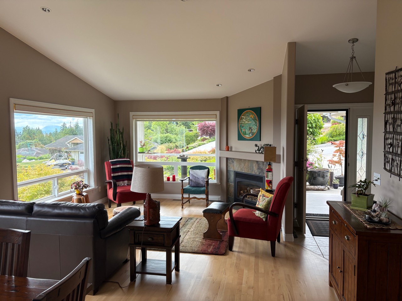 Main living area with fireplace, large windows, and garden outlook at 6252 Baillie Road